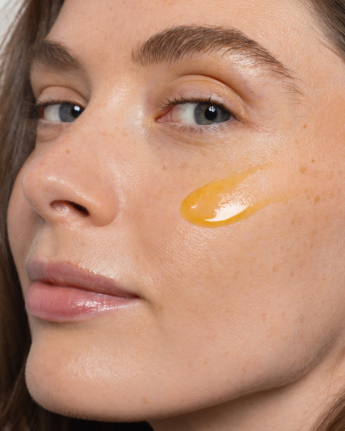 Sérum Booster de Vitamina C aplicado sobre la mejilla